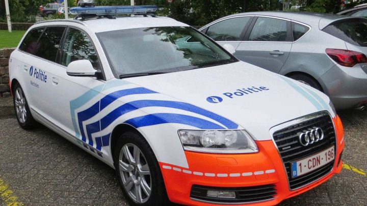 Belgische politiewagen met strepen en het opschrift Politie, geparkeerd op straat