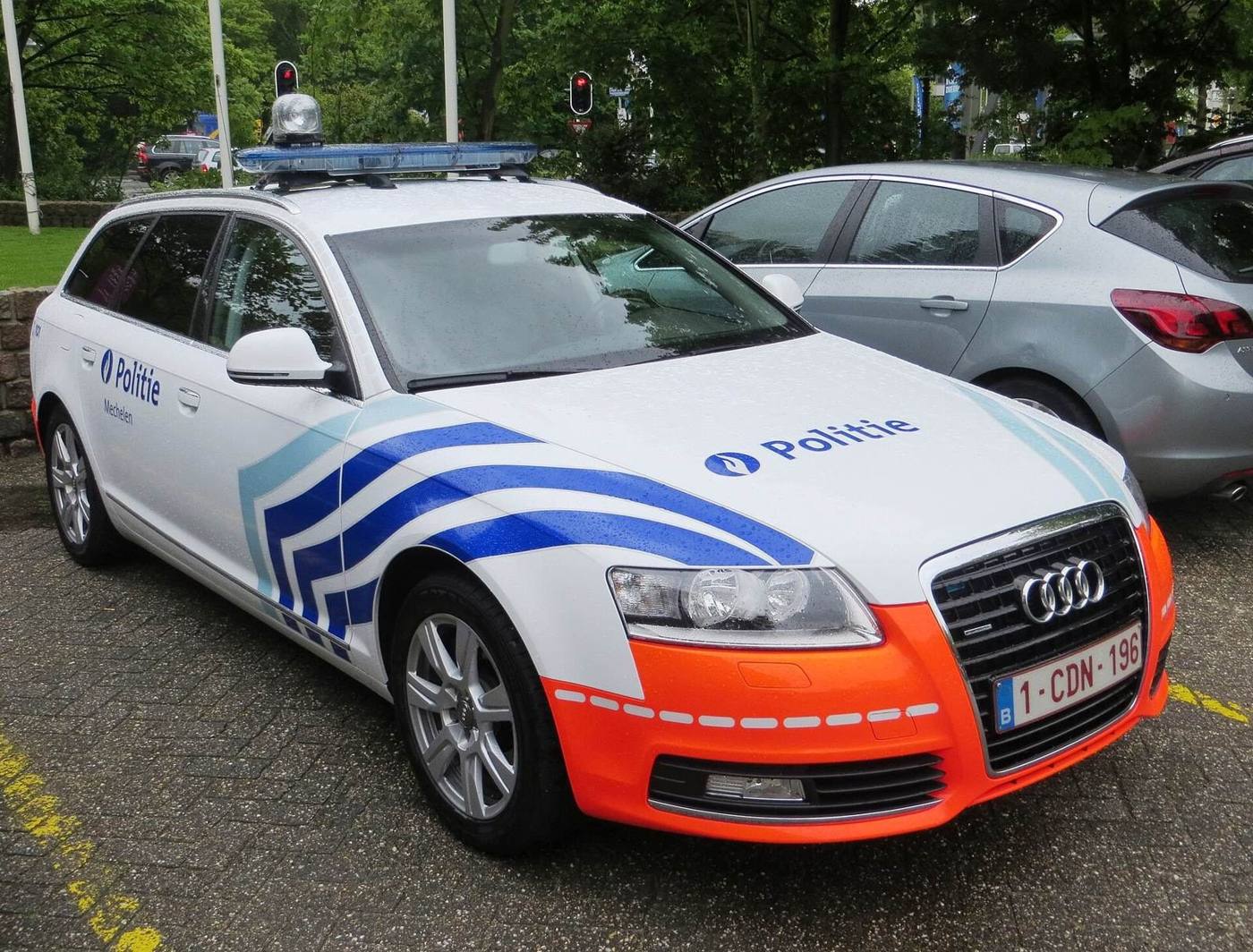 Belgische politiewagen met strepen en het opschrift Politie, geparkeerd op straat